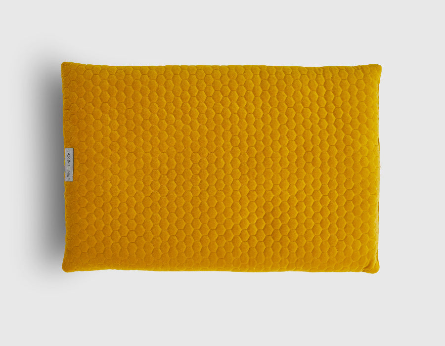 Yellow quilted pillow dog bed on a light gray background